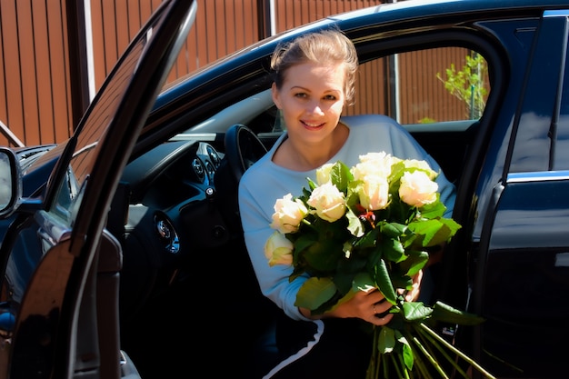 belle femme avec des fleurs dans une voiture chère.