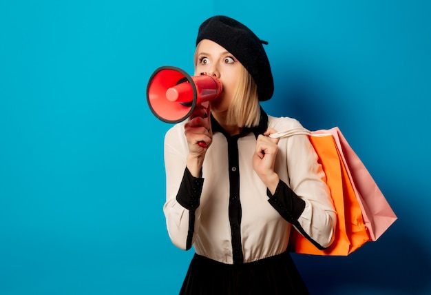 Belle femme française en béret avec sacs et haut-parleur