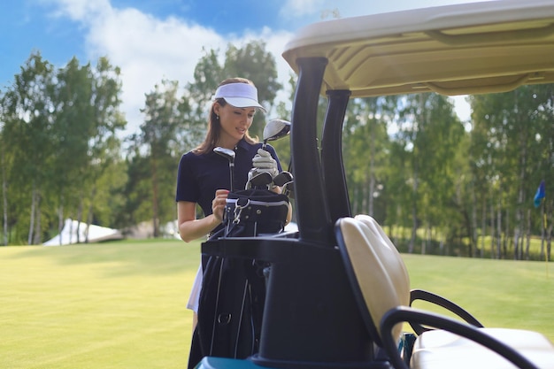 Photo belle femme gaie debout près de la voiturette de golf.