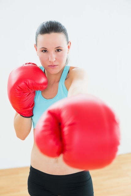 Belle femme en gants de boxe rouges au studio de remise en forme