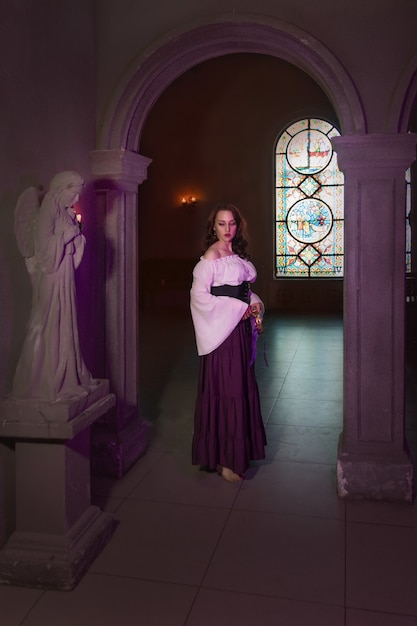 Belle femme gitane en gros plan dans la pièce sombre de l'église cathédrale avec tambourin de musique à la main