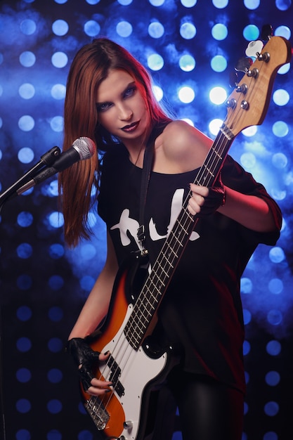 Belle femme avec une guitare dans les mains de l'exécution sur scène dans un style rock