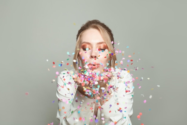 Une belle femme heureuse et des confettis colorés sur un fond gris