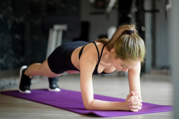 Une belle femme heureuse fait du yoga sur tapis à la salle de sport, concept de mode de vie sain, sports, entraînement, bien-être et sport.