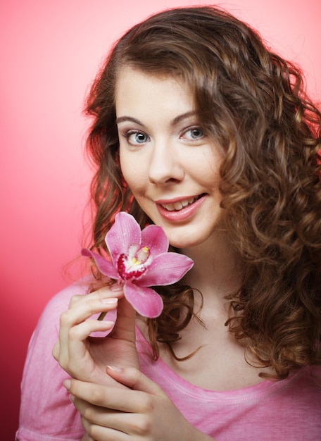 Belle femme heureuse avec fleur d'orchidée sur fond rose