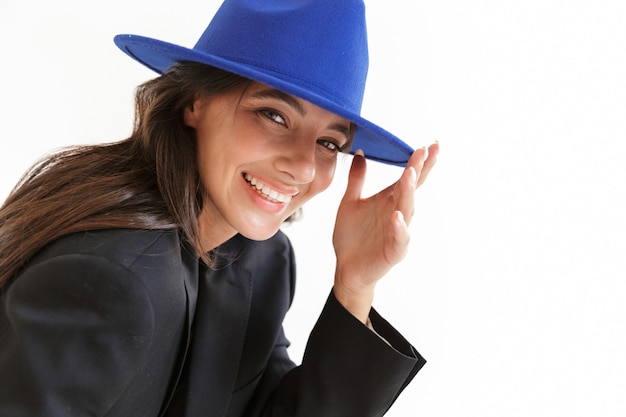 une belle femme heureuse joyeuse et optimiste au chapeau bleu posant isolée.