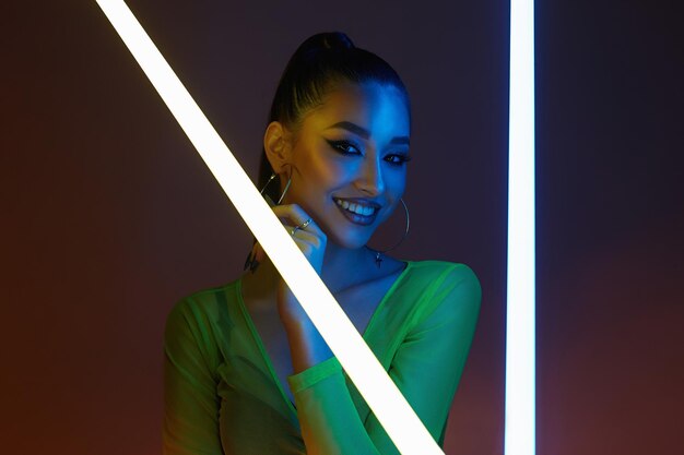 Photo belle femme heureuse avec lampe au néon jolie fille souriante en portrait en studio de lumières de couleur