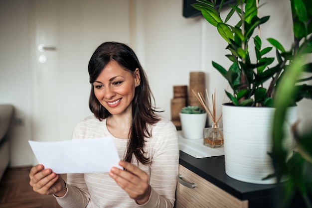 Belle femme heureuse occasionnelle regardant la lettre reçue.