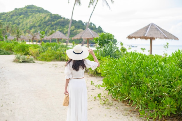 Une belle femme heureuse en robe blanche appréciant et relaxant sur la plage, concept d'été et de vacances