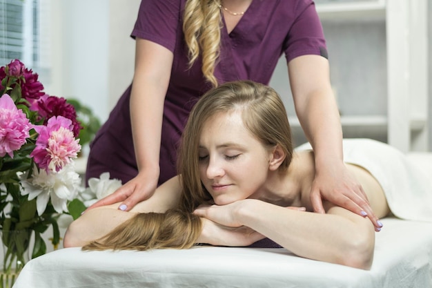 Belle femme heureuse se trouve dans un salon spa et bénéficie d'un massage professionnel. Environnement agréable dans un salon de beauté.