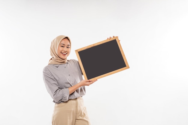 Une belle femme avec hijab debout et montrant avec enthousiasme le tableau noir