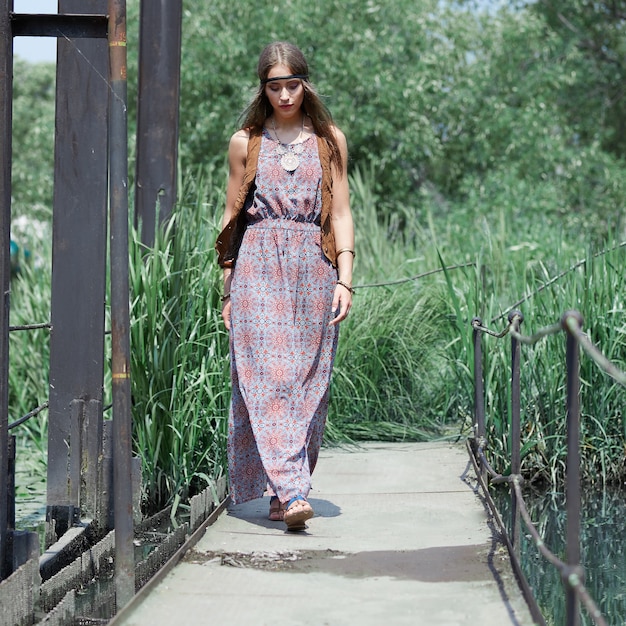 Belle femme hippie marchant sur un pont en bois dans le parc