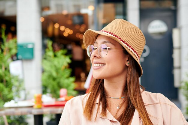 Une belle femme hispanique dans un chapeau assis dans un café par une journée ensoleillée