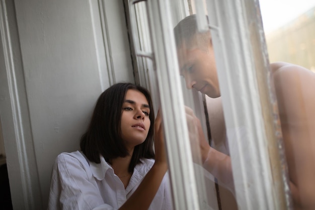 belle femme et homme se touchent les mains à travers le verre