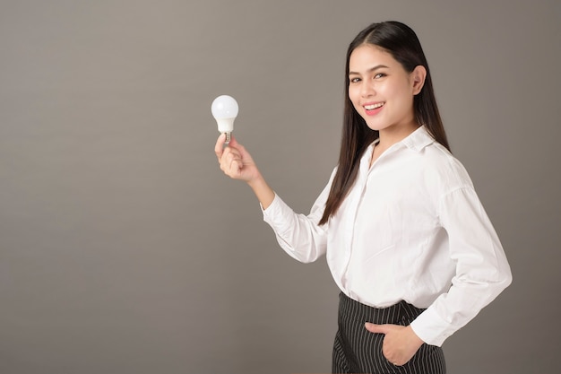 Belle femme intelligente tient une ampoule en studio