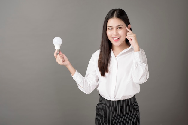 Belle femme intelligente tient une ampoule