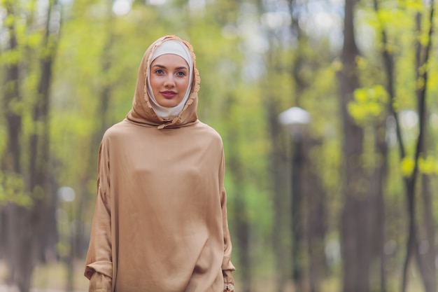 Belle femme islamique dans une robe musulmane debout sur un fond de rue de parc d'été arbres forestiers d'automne