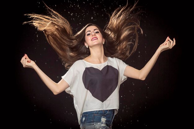 Belle femme a jeté ses cheveux sur un fond noir avec des gouttes d'eau