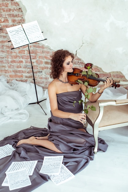 Belle femme jouant de l'archet de violon rose