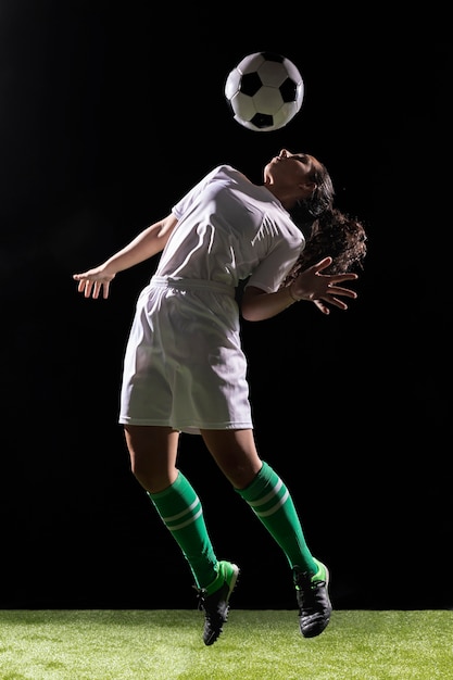 Photo belle femme jouant avec un ballon de foot