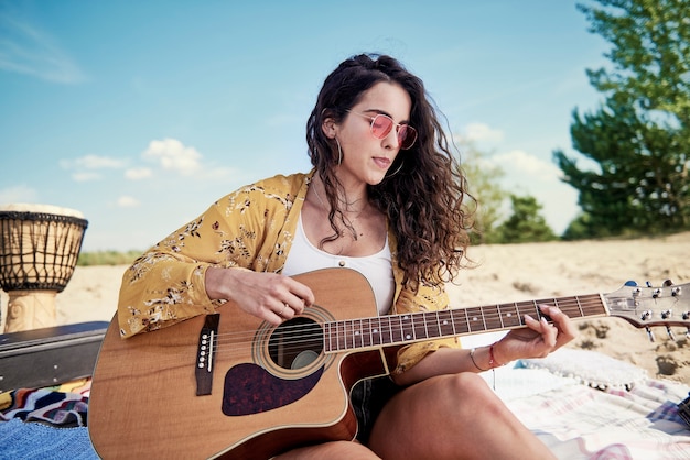 Belle femme jouant de la guitare sur la plage