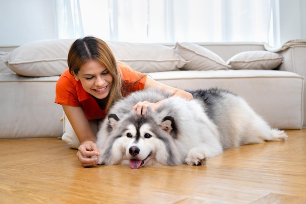 Belle femme jouant avec son chien dans la chambre à la maison avec bonheur
