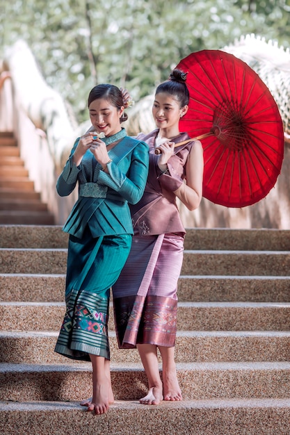 Belle femme laotienne en costume national debout regardant les fleurs avant d'entrer dans le temple