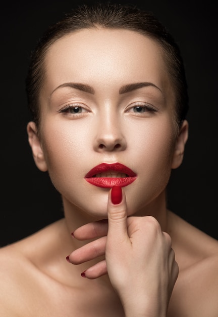 Photo belle femme avec des lèvres rouges se touchant les lèvres.