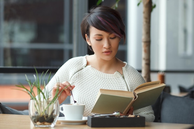 Belle femme lisant un livre au café