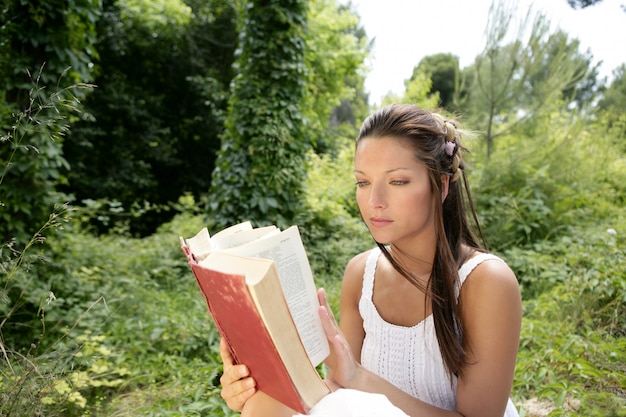 Belle femme lisant un livre dans la forêt, nature