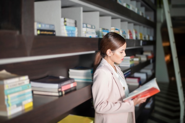 Belle femme lit des livres dans la bibliothèque