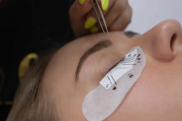 Belle femme avec de longs cils dans une procédure d'extension de cils de salon de beauté cils se bouchent