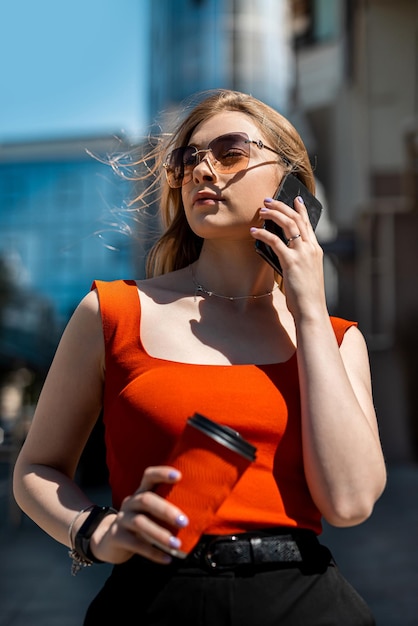 Belle femme avec des lunettes et marchant et parlant au téléphone mobile Communication sans fil