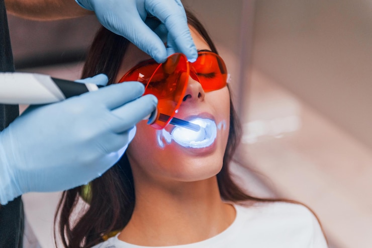 Photo belle femme à lunettes de protection rouges a une visite à la clinique du dentiste. conception de la stomatologie.