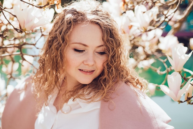 Belle femme luxueuse profitant d'une promenade dans le parc au soleil, posant et souriant