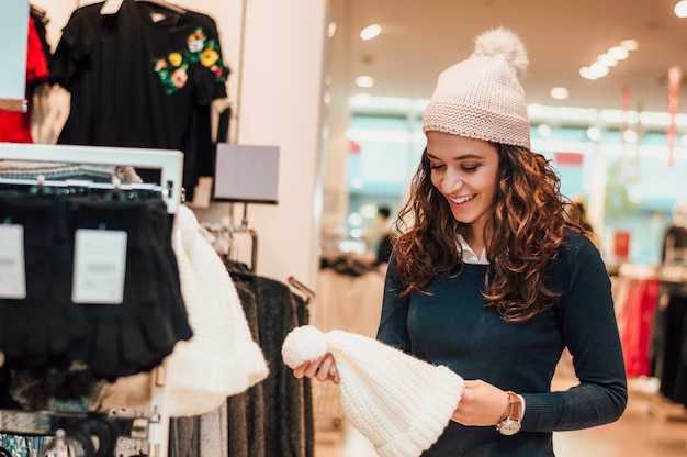 Belle femme en magasin achetant un chapeau.