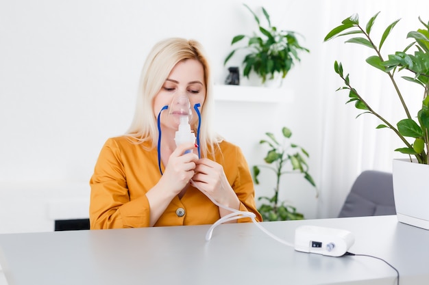 Une belle femme malade tient un masque nasal avec un problème respiratoire dans la chambre d'hôpital. traitement par inhalation d'une patiente par le masque de l'inhalateur avec un flux de fumée doux provenant du bronchodilatateur.