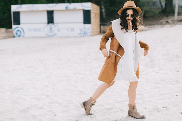 Belle femme en manteau marchant sur la plage