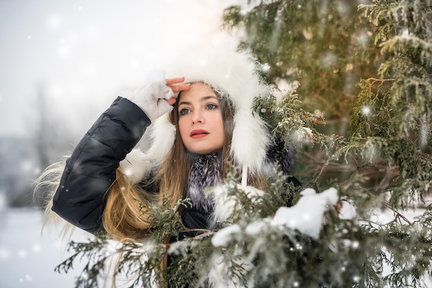 Belle femme en manteau noir en plein air dans le parc d'hiver