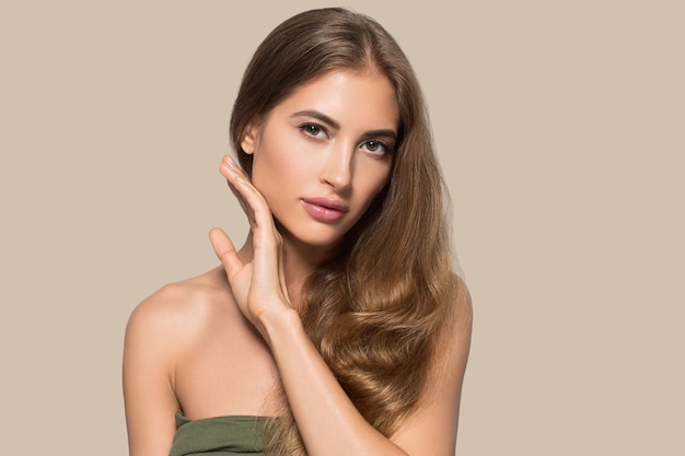 Belle femme avec maquillage naturel cosmétique quotidien décontracté touchant son visage. Couleur de fond Marron