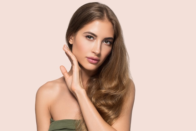 Belle femme avec maquillage naturel cosmétique quotidien décontracté touchant son visage. Couleur de fond Rose