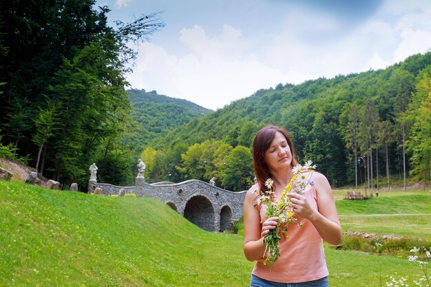 Belle femme marchant dans le champ avec un bouquet de fleurs