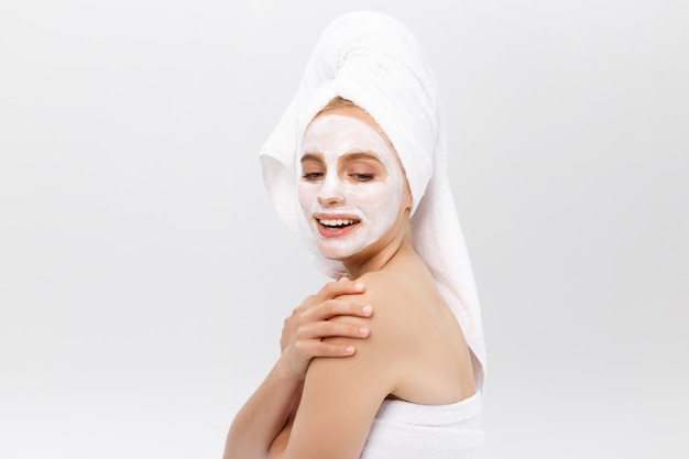 Belle femme avec un masque facial sur fond blanc