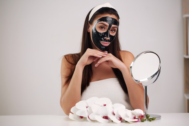 Photo belle femme avec un masque noir nettoyant sur son visage.