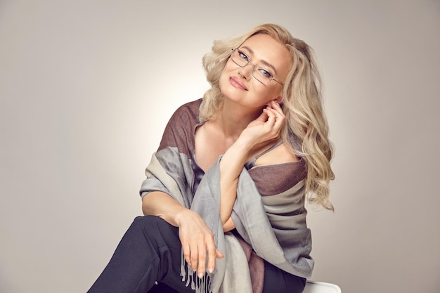 Belle femme mature aux cheveux blonds porte des lunettes optiques sur un fond gris isolé