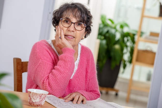 Belle femme mature brune s&#39;habillant en journal de lecture rose