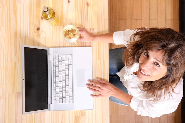 Une Belle Femme Mature Avec Un Verre De Vin Blanc Devant L'ordinateur Portable.