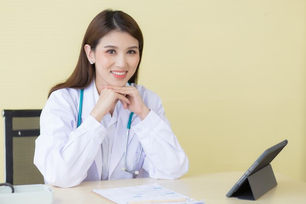 Une belle femme médecin asiatique attend d'être examinée dans la salle d'examen.