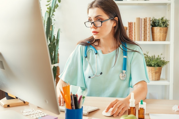 Belle femme médecin assise à sa table dans un cabinet médical