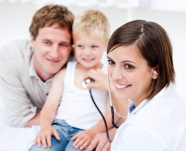 Belle femme médecin examinant un petit garçon avec son père